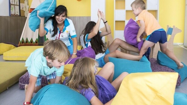 Un grupo de niños jugando en una habitación con cojines de colores y un ambiente alegre.