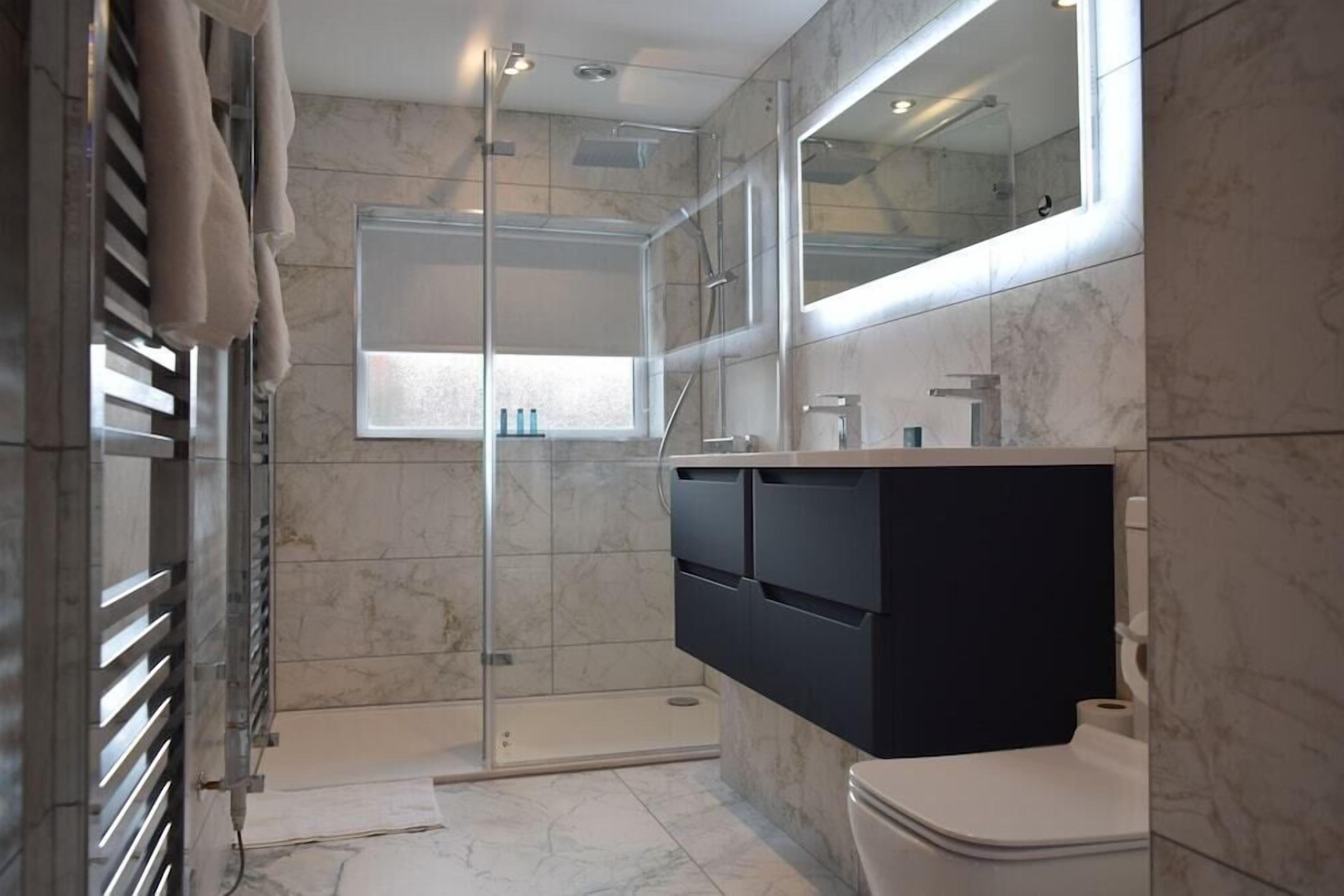 A modern bathroom with a glass-enclosed shower, a large mirror, and a black vanity.