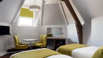 A hotel room with two beds, a small table, two chairs, a TV, and a window.