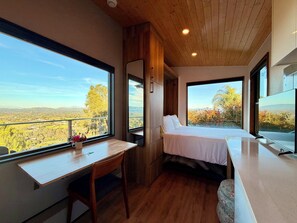 A bedroom with a large window, a wooden desk, and a bed. - Sanctuary Modern Tiny Home, Endless Panoramic Views, Hardwood Deck, Pool and Spa (Fallbrook)