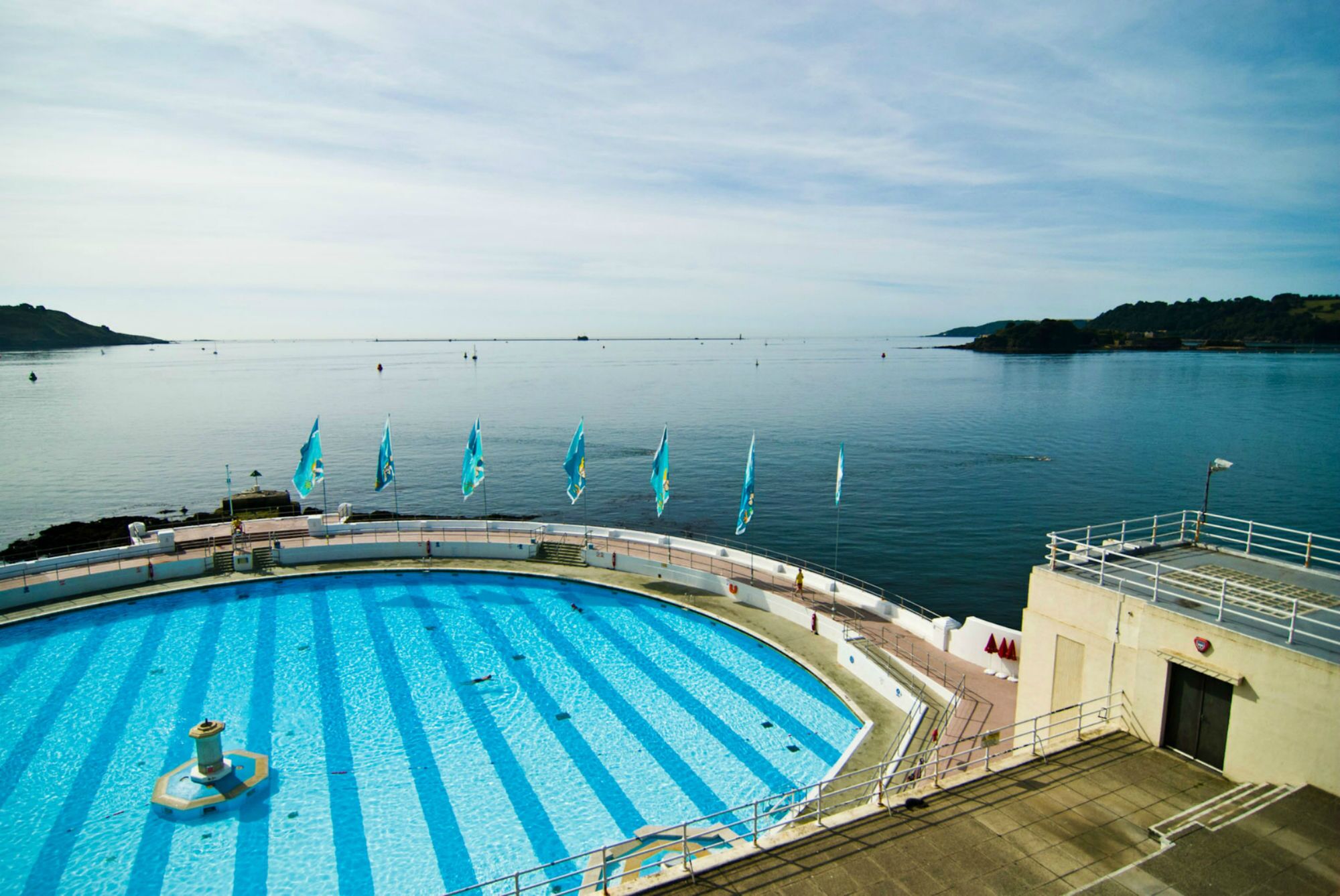 A swimming pool with clear blue water, surrounded by a deck with a railing.