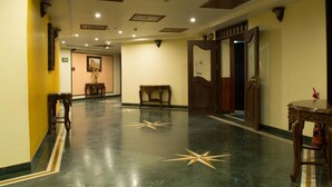 A hotel corridor with a polished floor, wooden furniture, and a door with a decorative panel. - OYO Premium Nayapalli IRC Village (Bhubaneshwar)