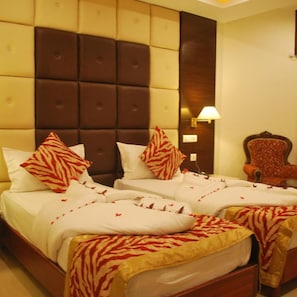 Een hotelkamer met een groot bed, twee kussens, een nachtkastje, een lamp en een stoel.