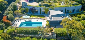 Vue aérienne d’une maison moderne dotée d’une piscine, de chemins en pierre et d’une végétation luxuriante.