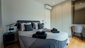 Ein modernes Schlafzimmer mit einem Bett, einem Sessel, einem Schreibtisch und einer Klimaanlage.