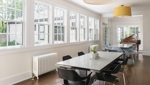 Ein geräumiger Raum mit einem langen Tisch, mehreren Stühlen und großen Fenstern.