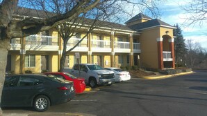 A multi-story motel with a parking lot, cars parked in front, and a tree in the foreground. - Extended Stay America - Washington DC - Chantilly (Chantilly)