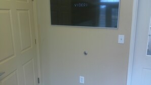 A wall-mounted flat-screen TV with the word 'VIDERI' on it, a door with a handle, and a light switch. - Extended Stay America - Washington DC - Chantilly (Chantilly)