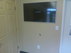 A wall-mounted flat-screen TV with the word 'VIDERI' on it, a door with a handle, and a light switch. - Extended Stay America - Washington DC - Chantilly (Chantilly)