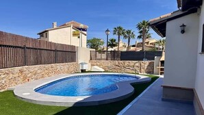 Une piscine avec un mur en pierre et une clôture en bois en arrière-plan.