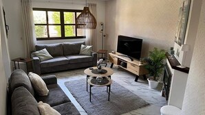 Un salon avec un canapé, une table basse, un téléviseur et une plante en pot.