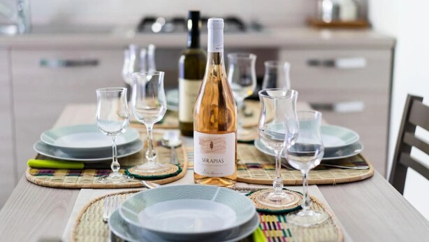 A dining table set with plates, glasses, and a bottle of wine. - Estate4home - Casa Cinzia (Vico Equense)