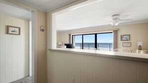 A room with a balcony overlooking the ocean, a ceiling fan, and a view of the sea.
