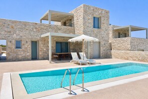 A stone building with a pool, outdoor seating, and a pergola. - Villa Lithos Sea View (Paros)
