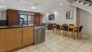 Una cocina moderna con armarios de madera, lavavajillas y un comedor con mesa y sillas.