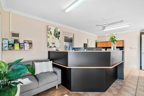 Una sala moderna con un sofá gris, un mueble de entretenimiento negro y un ventilador de techo.
