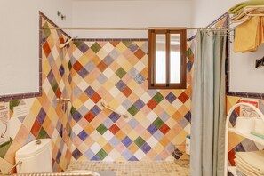 A bathroom with a colorful diamond-patterned tile wall, a shower area, and a toilet. - Country House 'La Sierrezuela - Families Only' with Mountain Views, Wi-Fi & Air Conditioning (Posadas)