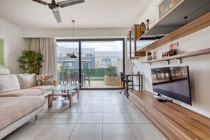 A modern living room with a sofa, coffee table, TV, and a balcony with plants. - Elegant apartment, large sun terrace, hot tub SMAS1-1 (Marsaskala)