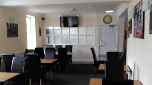 A conference room with tables and chairs, a clock on the wall, and a door. - Morpeth Lodge (Morpeth)