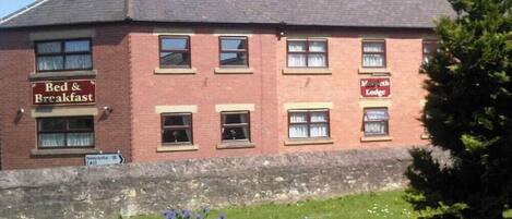 A red brick building with a sign for 'Bed & Breakfast' and 'Morpeth Lodge'.