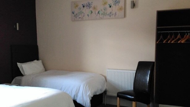 A bedroom with a bed, a chair, and a wardrobe. - Morpeth Lodge (Morpeth)