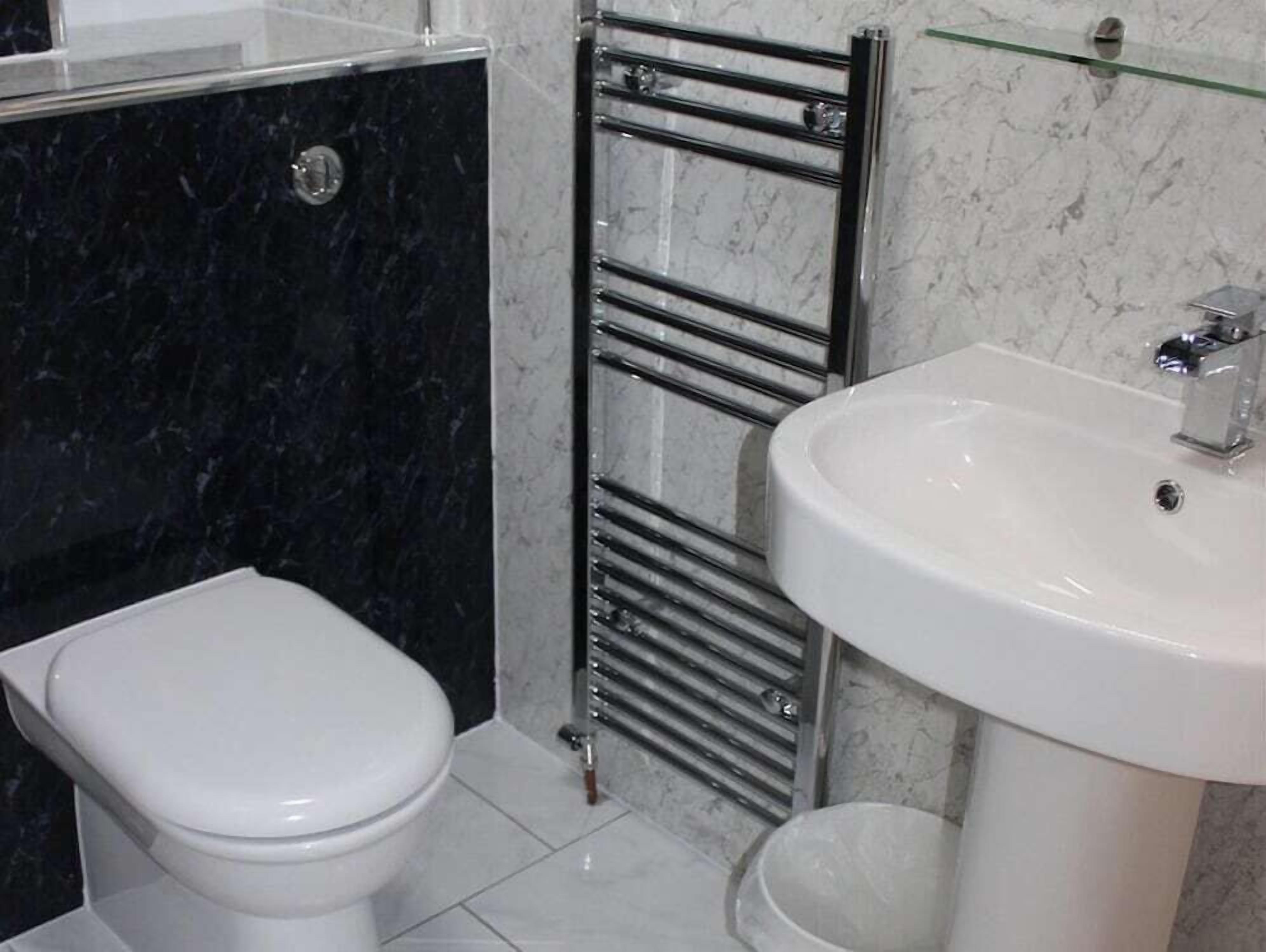 Un baño con inodoro, lavamanos y toallero.