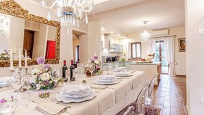 Ein langer Esstisch, festlich gedeckt für ein formelles Essen, mit weißen Tischdecken, Besteck und Kristallgläsern.