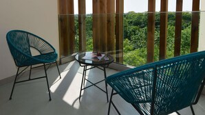 En balkon med to turkise stole, et lille rundt bord og udsigt over et grønt landskab.
