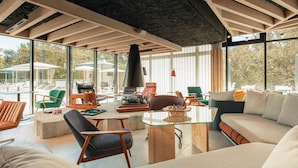 A spacious living area with a glass table, comfortable seating, and a large window offering a view of the outdoors.