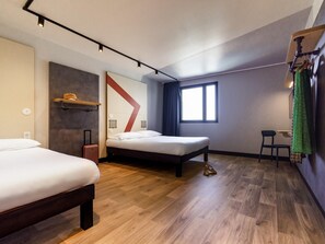 Ein modernes Hotelzimmer mit zwei Betten, einem Schreibtisch, einem Stuhl, einem Fenster und einem einzigartigen Wanddesign.