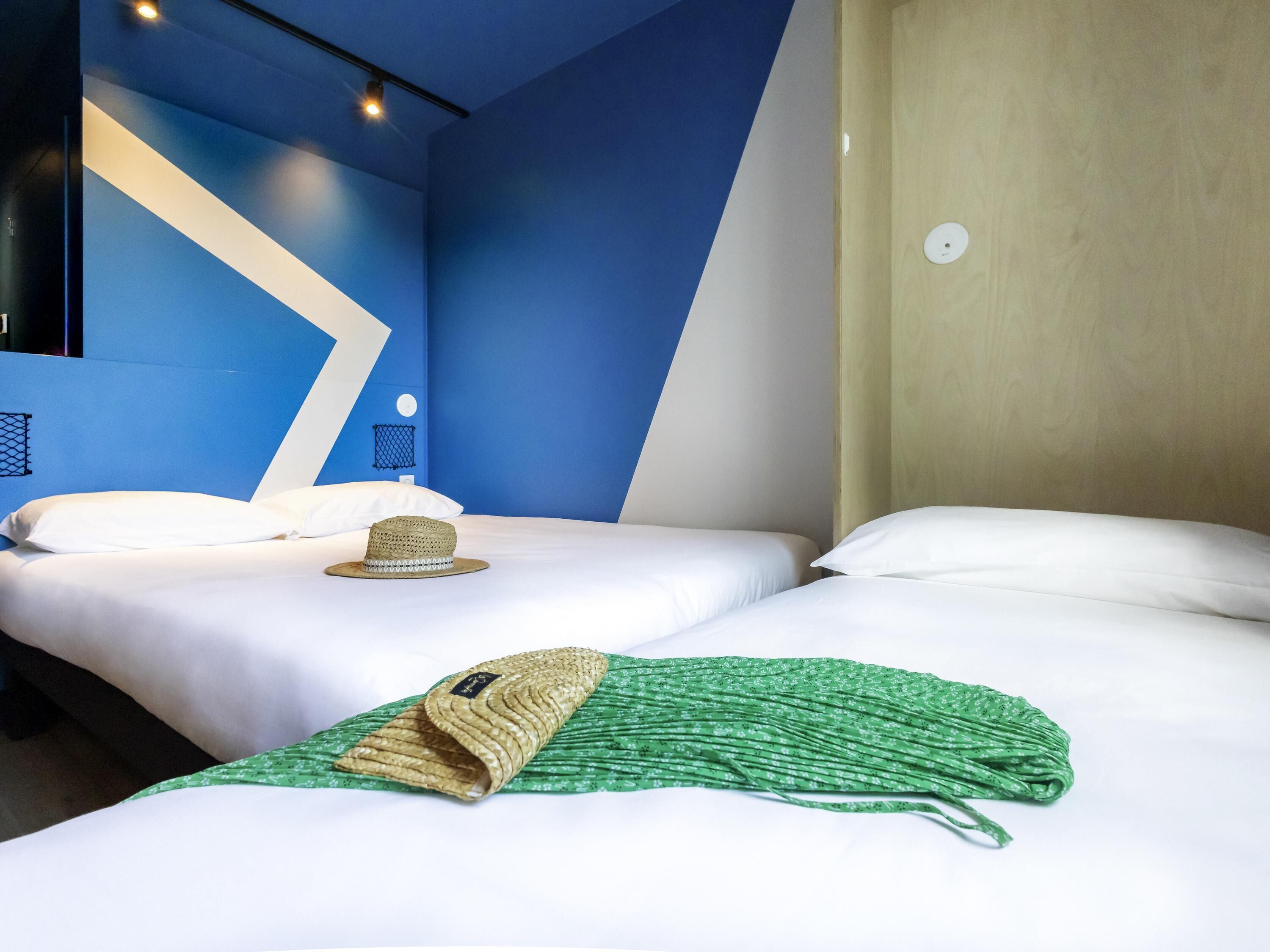 Una habitación de hotel con dos camas, un sombrero y una toalla verde en el suelo.