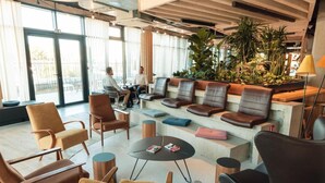 Et moderne loungeområde med læderpolstret møbler, et sofabord og potteplanter.