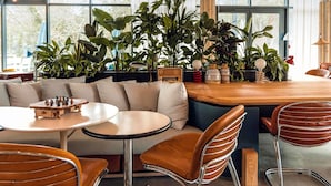 A modern interior with a wooden table, leather chairs, a sofa, and a variety of plants.