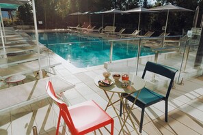 A poolside area with a glass table, chairs, and a dining set. - Ibis Budget La Rochelle Centre (La Rochelle)