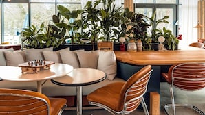 Et moderne interiør med et træbord, læderstole, en sofa og mange planter.