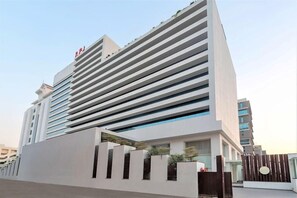 A modern hotel with a prominent 'RJI' sign, featuring a clean, white facade with horizontal lines and large windows. - Regenta Central Rajkot (Rajkot)