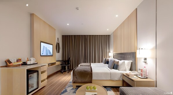 Een moderne hotelkamer met een bed, nachtkastje, bureau en een televisie.