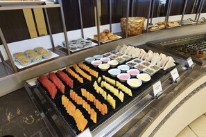 Un bufé con diversas opciones de comida, incluyendo carnes, quesos y pasteles.