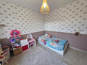 Ein Kinderzimmer mit Bett, Kommode, Spiegel und einer Deckenleuchte.