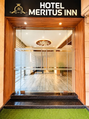 Een hotelentree met een modern design, voorzien van een glazen deur, een houten omlijsting en een logo boven de naam.