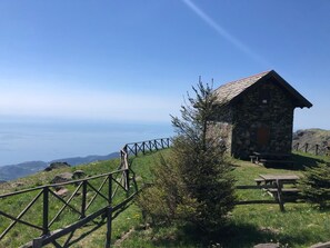 A stone cabin with a picnic table and a wooden fence, overlooking a mountainous landscape. - Nice apartment for 3 guests with WIFI and pets allowed (Urbe)