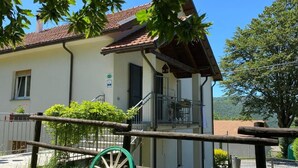 Ein zweistöckiges Haus mit Balkon, Holzzaun und einem grünen Laufrad im Vordergrund.