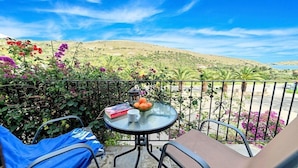 Een balkon met een tafel, stoelen en uitzicht over een glooiend landschap.