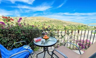 Un balcón con una mesa, sillas y vistas a un paisaje montañoso.