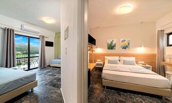 Habitación de hotel con cama, escritorio, silla, televisor y balcón con vistas.