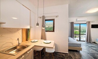 Cocina compacta con pileta, comedor con mesa y sillas, y balcón con vista.