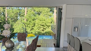 Una cocina moderna con armarios blancos, una mesa de comedor con sillas a rayas y vistas al exterior.