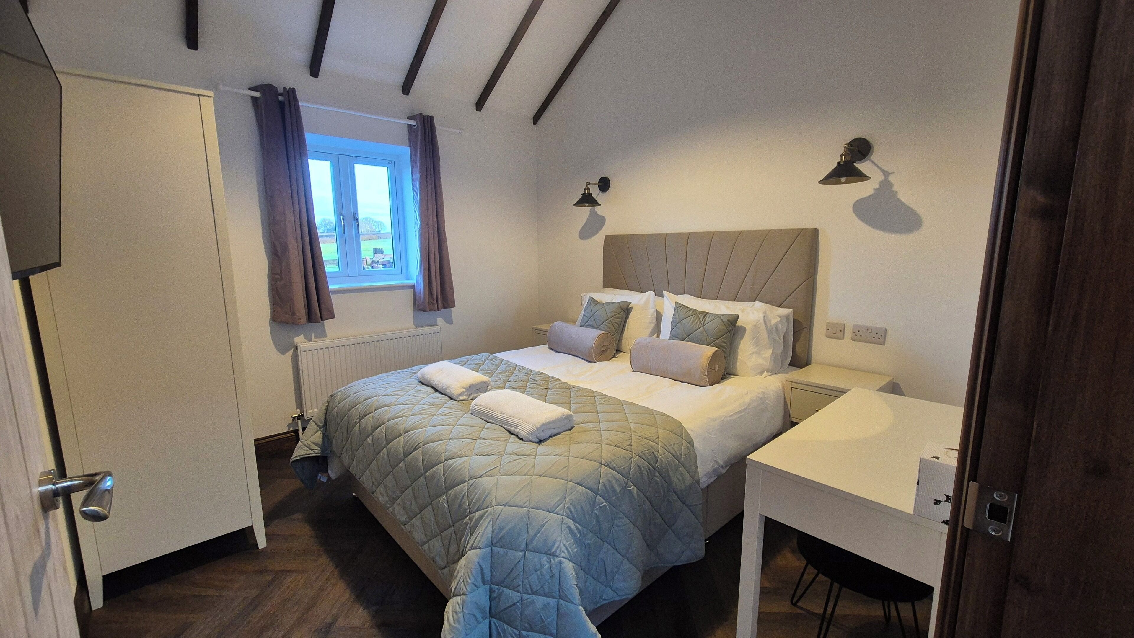 A bedroom with a bed, bedside tables, a window with curtains, and a radiator.