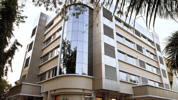 A modern multi-story building with a curved facade, large windows, and ventilation grilles.