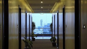 A corridor with doors leading to rooms, potted plants, and a view of buildings outside. - Keys Hotel Vihas (Tirupati)